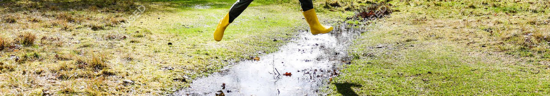 focused_166079550-stock-photo-boy-yellow-anorak-jumping-puddle